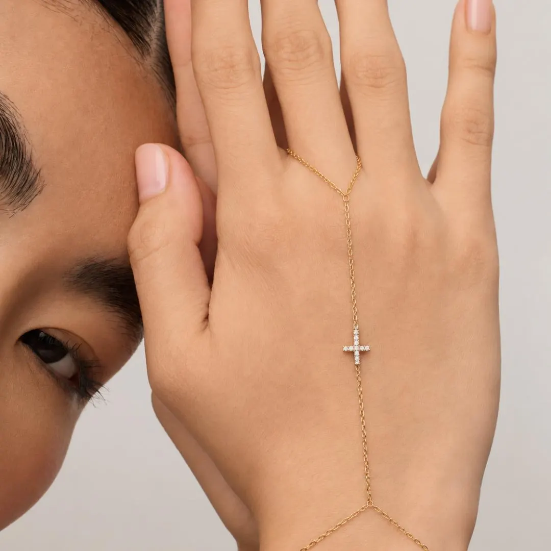 Yellow gold diamond cross hand chain bracelet worn with delicate finger loop