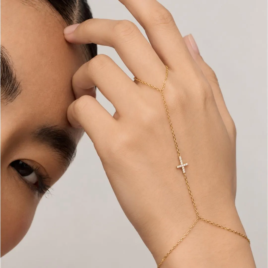 Yellow gold diamond cross hand chain bracelet worn with delicate finger loop