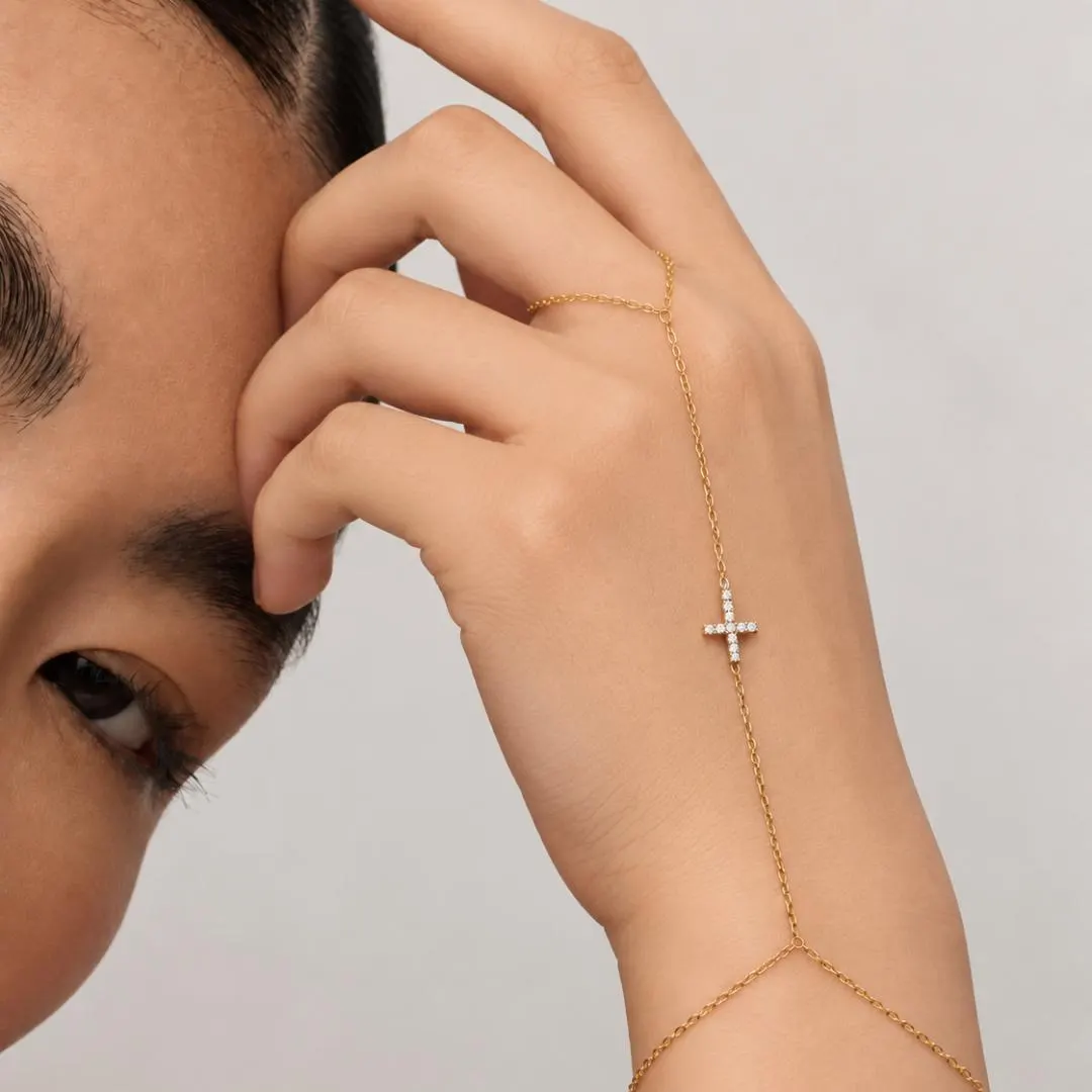 Yellow gold diamond cross hand chain bracelet worn with delicate finger loop