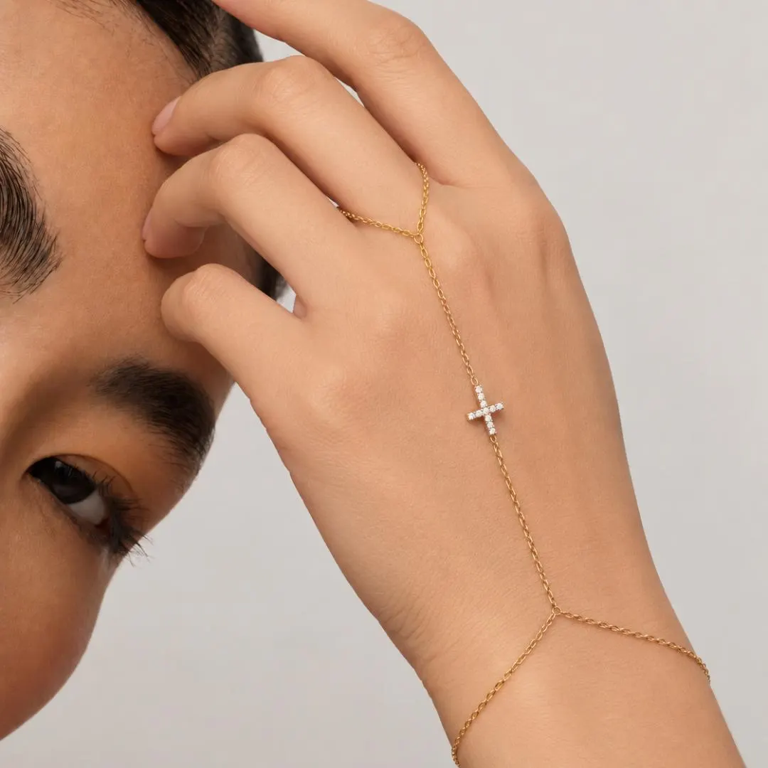 Yellow gold diamond cross hand chain bracelet worn with delicate finger loop