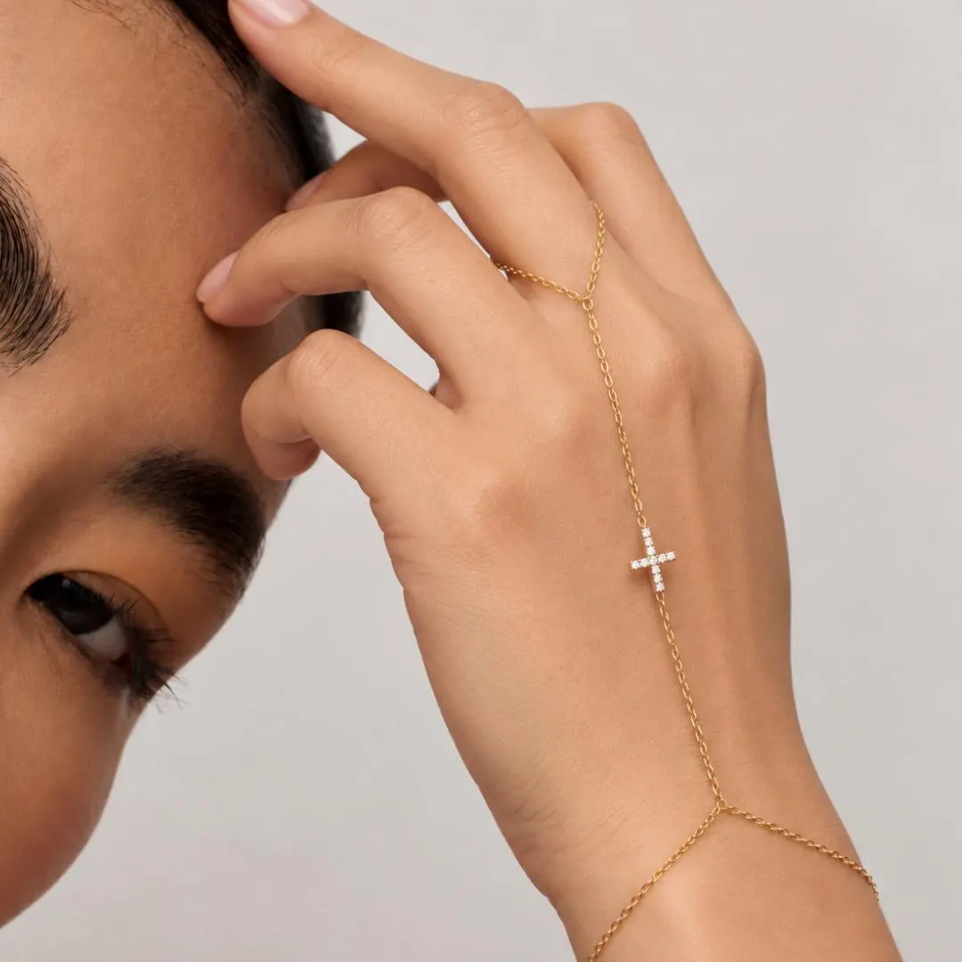 Yellow gold diamond cross hand chain bracelet worn with delicate finger loop